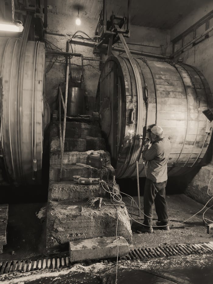 A man operates large industrial machinery in a workshop, showcasing manual labor in a workshop.